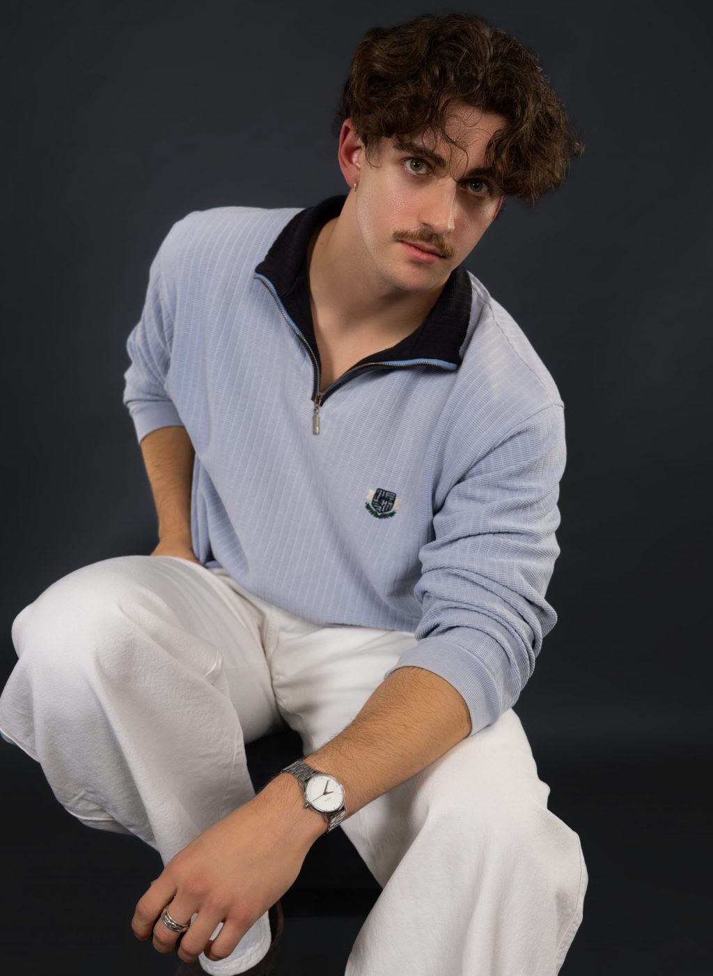 DSC_0884-Bearbeitet-markus-hell-blauer-pullover-sitzend-weiße-hose-schwarzer-hintergrund