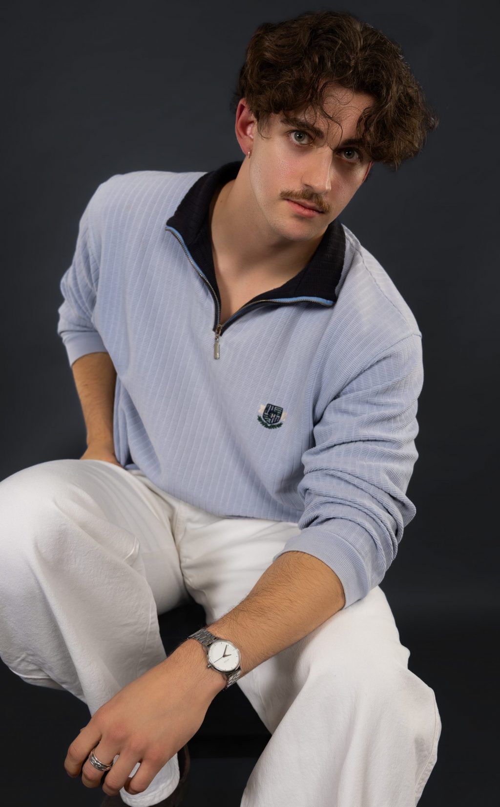 DSC_0884-Bearbeitet-markus-hell-blauer-pullover-sitzend-weiße-hose-schwarzer-hintergrund